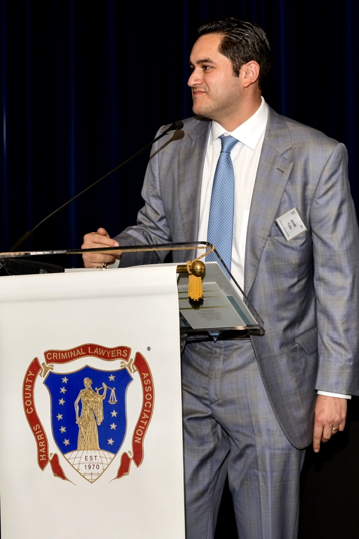 Jacob Vela speaking at a Harris County Criminal Lawyers Association podium